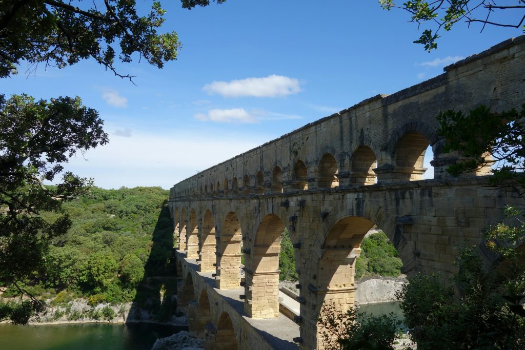 La Création Logo Nîmes, Captivating shot of the historic Pont du Gard aqueduct against a clear blue sky.